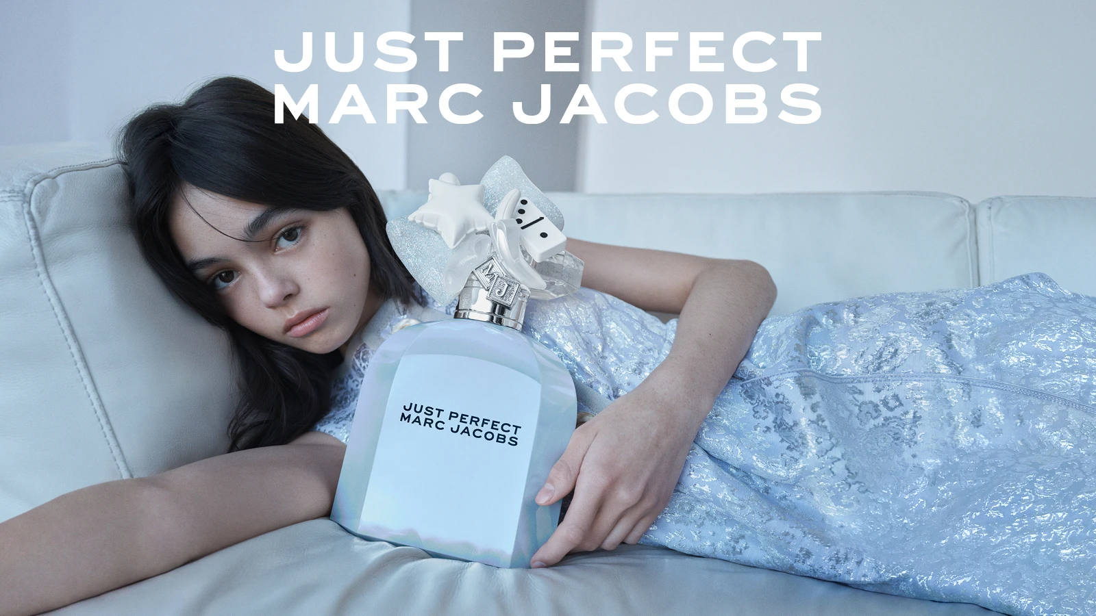 Person holder stor, iriserende Marc Jacobs parfume. Flaske og billede med teksten 'JUST PERFECT MARC JACOBS'.