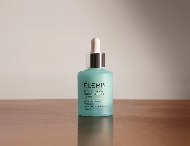 Her ses et ELEMIS serum i en glasflaske med pipette på en lys baggrund.