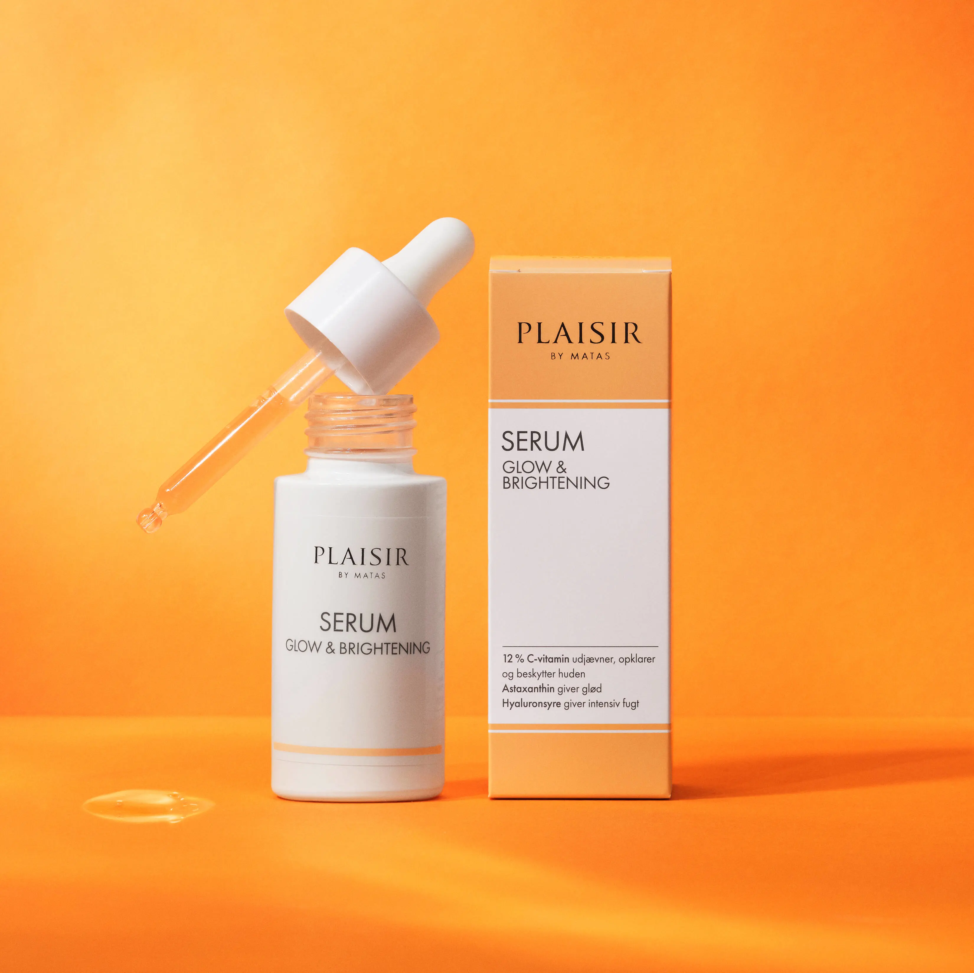 Produktbillede af et serum fra “Plaisir by Matas” på en varm orange baggrund. Til venstre står en hvid serumflaske med teksten “Serum Glow & Brightening”. Pipetten ligger skråt oven på den åbne flaske med en dråbe serum i spidsen, og lidt væske er dryppet ned på overfladen foran produktet. Til højre står den tilhørende produktæske i hvide og lyse orange farver med produktnavn og beskrivelse. Billedet har et rent og moderne udtryk med fokus på glødgivende hudpleje.