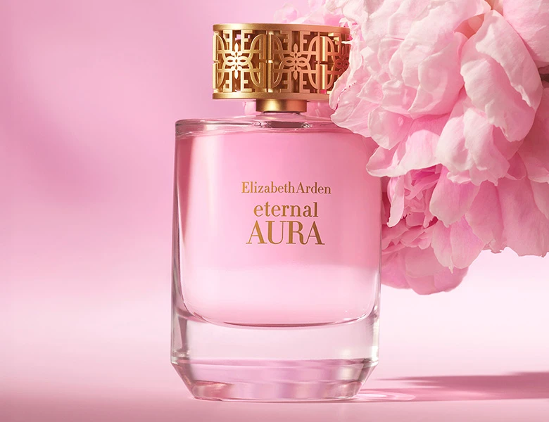 Her ses en Elizabeth Arden parfume i en lyserød flaske ved siden af en lyserød blomst på en lyserød baggrund.