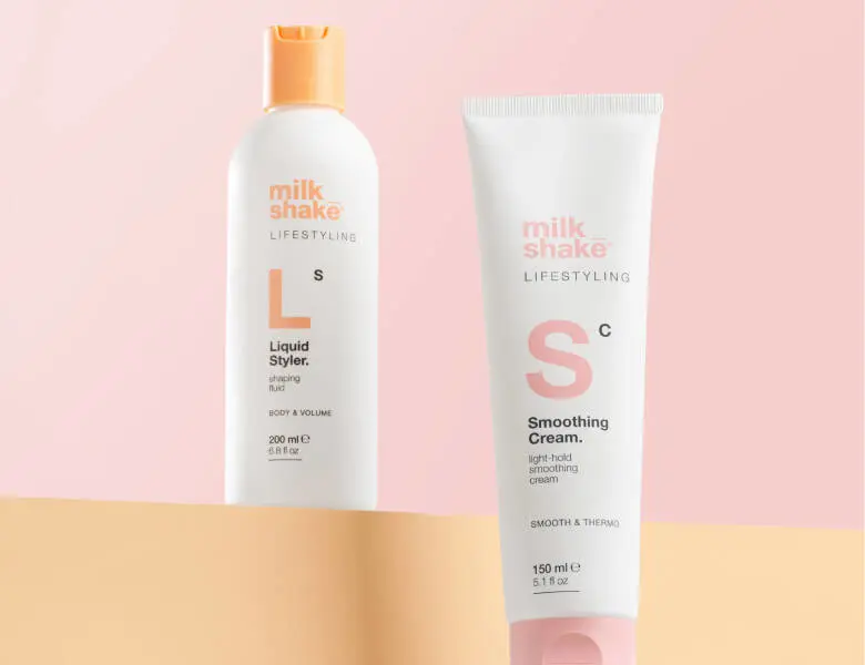 Her ses et billede med to hårprodukter fra milk_shake placeret mod en lyserød baggrund. På produkterne står teksten “milk_shake LIFESTYLING”, “Liquid Styler” og “Smoothing Cream”. Produkterne er i hvide emballager med orange og lyserøde detaljer.