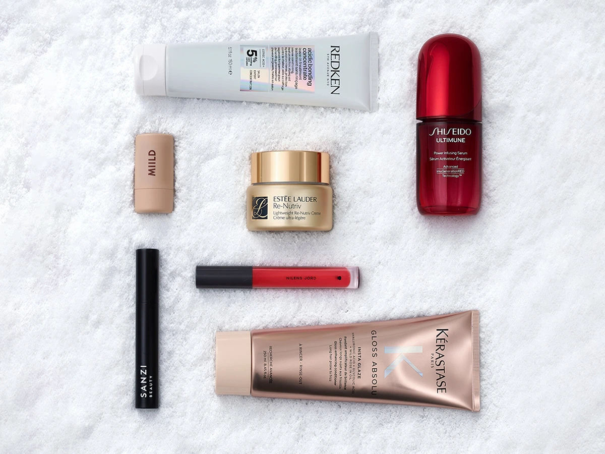 En samling af skønhedsprodukter, inklusive hårpleje, hudpleje og makeup, arrangeret på en hvid overflade.