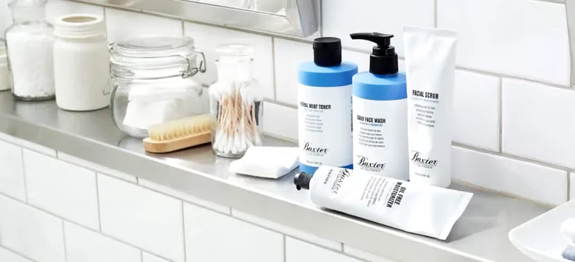 Her ses et badeværelse, hvor der blandt andet står fire Baxter of California produkter. Badeværelset er lavet af hvide klinker.