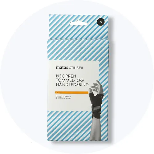 En pakke med Matas Striber Neopren tommel- og håndledsbind står på en lys grå baggrund. På emballagen ses en illustration af et håndled med bindet på.