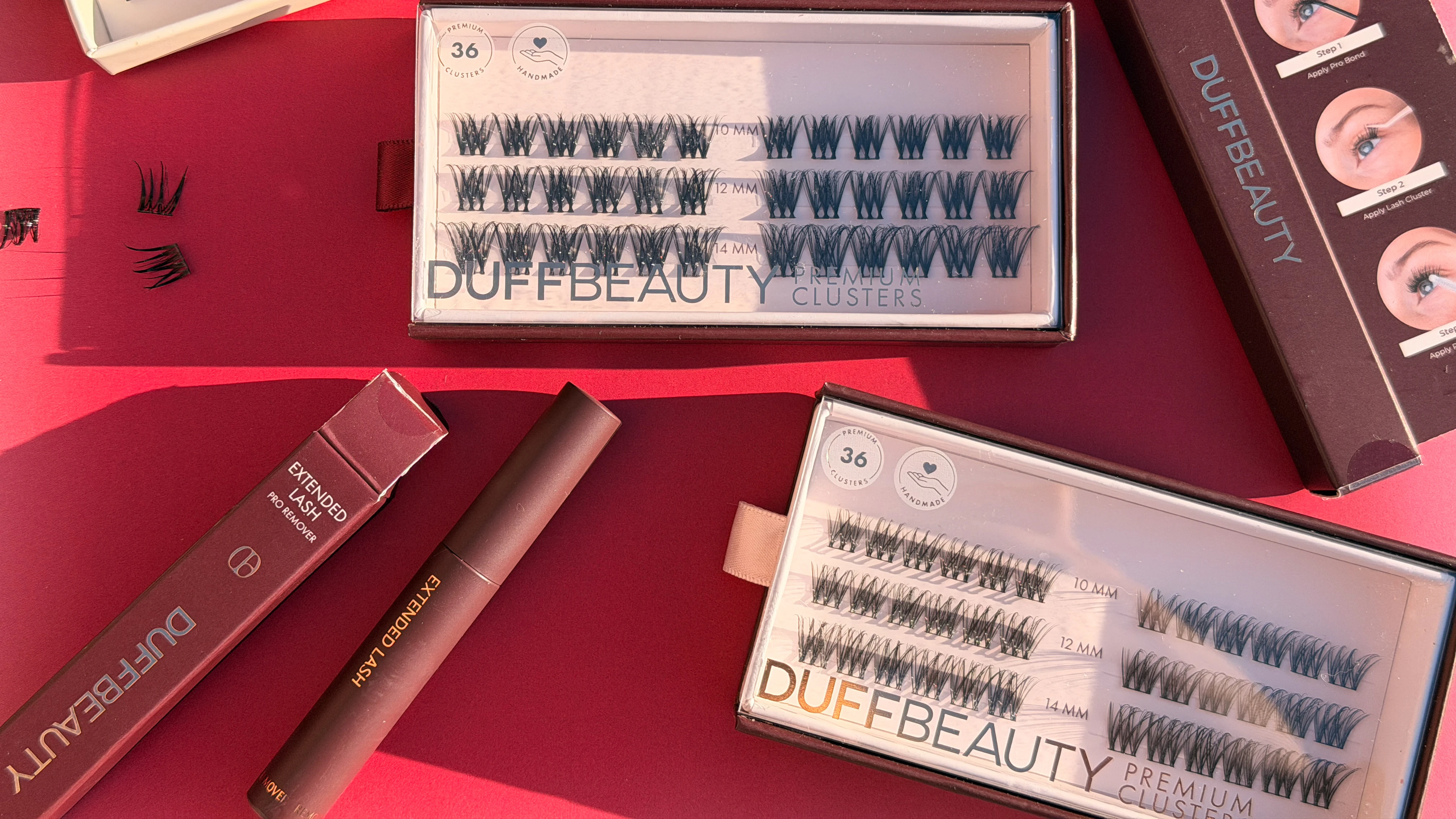 En person holder en åben æske med Duffbeauty Premium Clusters øjenvipper, der indeholder 36 klynger i 10 mm, 12 mm og 14 mm længder.