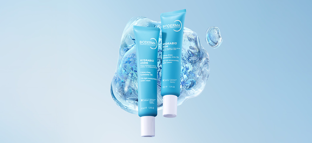 Her ses to BIODERMA Hydrabio ansigtscremer foran en blå baggrund med vanddråber.