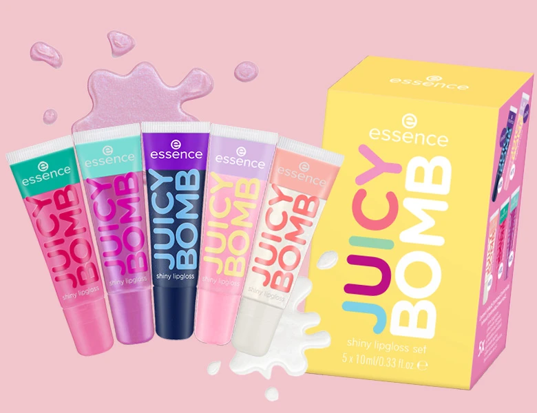 Her ses et billede med et Juicy Bomb-gaveæske fra essence mod en lyserød baggrund. Til venstre ses fem Juicy Bomb Shiny Lipgloss i forskellige farver, og til højre står gaveæsken med teksten “Juicy Bomb” og “Shiny Lipgloss Set”. Rundt om produkterne ses grafiske elementer, der ligner glansdråber og et stænk af lipgloss, som understreger det legende og farverige udtryk.