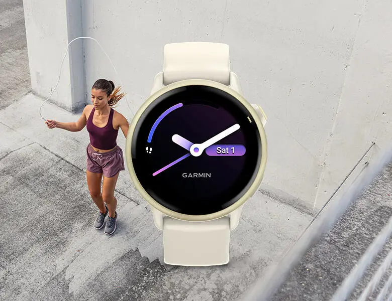 Kvinde træner udenfor og hopper med sjippetov ved en betontrappe, mens et lyst Garmin smartwatch med rund urskive vises stort i forgrunden.