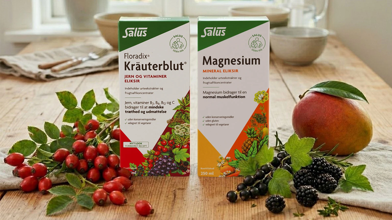 Salus Floradix Kräuterblut jern- og vitamineliksir og Salus Magnesium mineraleliksir. Omgivet af hyben, mango, solbær og brombær.