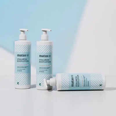 Her ses en lyseblå og hvid baggrund med tre blå og hvide hyaluron produkter fra Matas Striber. 