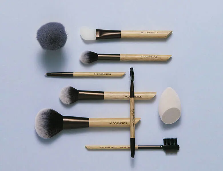 Her ses en masse forskellige M.Cosmetics produkter på en lilla baggrund.