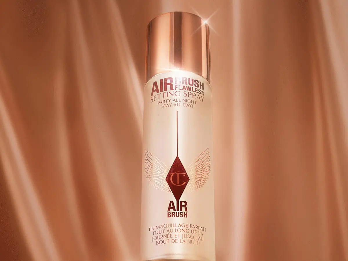 Hvid frostet flaske Charlotte Tilbury Airbrush Flawless Setting Spray med rosaguld låg. Tekst: 'AIRBRUSH FLAWLESS SETTING SPRAY', 'PARTY ALL NIGHT! STAY ALL DAY!', 'AIR BRUSH', 'UN MAQUILLAGE PARFAIT TOUT AU LONG DE LA JOURNÉE ET JUSQU'AU BOUT DE LA NUIT!'.