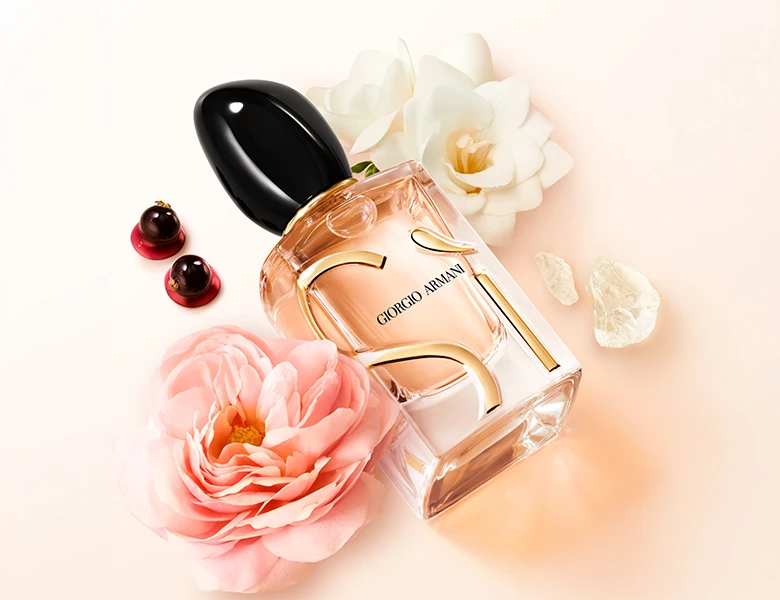 Her ses Giorgio Armani Sì-parfumen omgivet af blomster og bær på en lys baggrund.