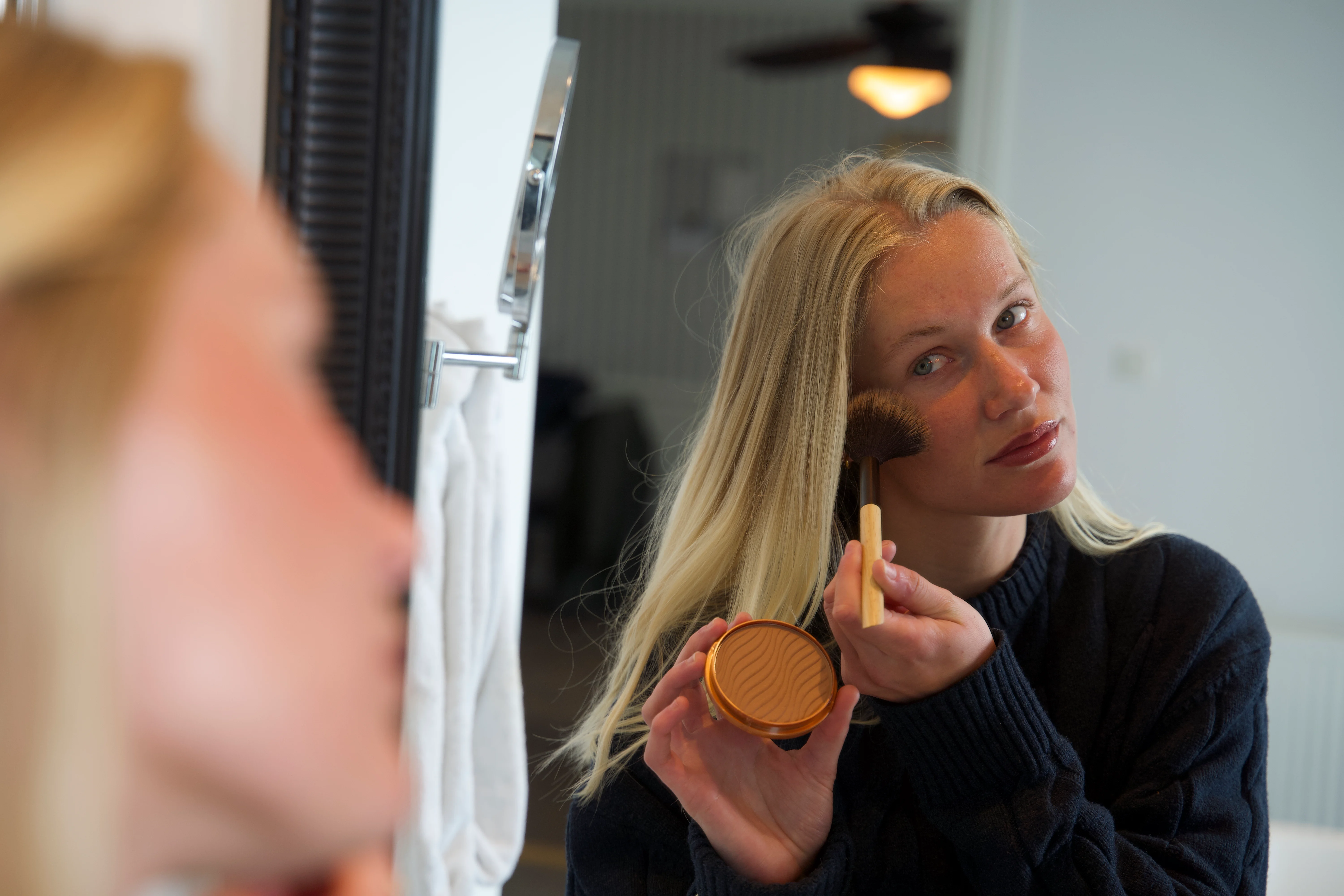 Kvinde, der påfører bronzer med en børste på kinden