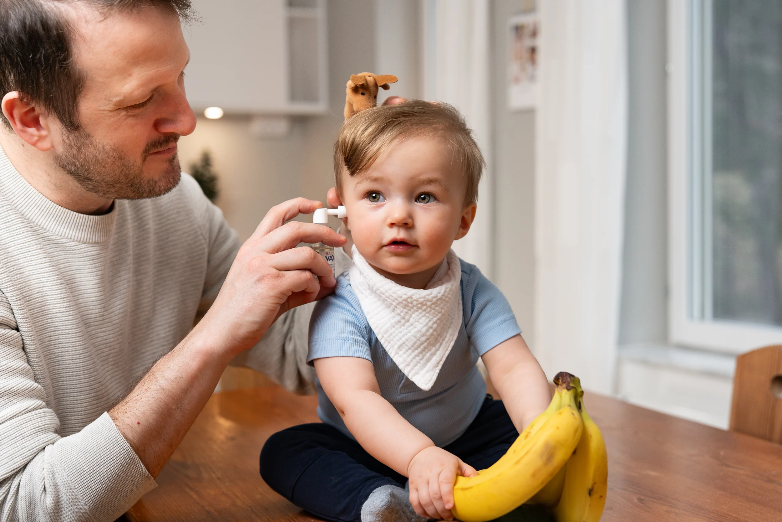 Far sætter Vaxol ørespray i øret på baby