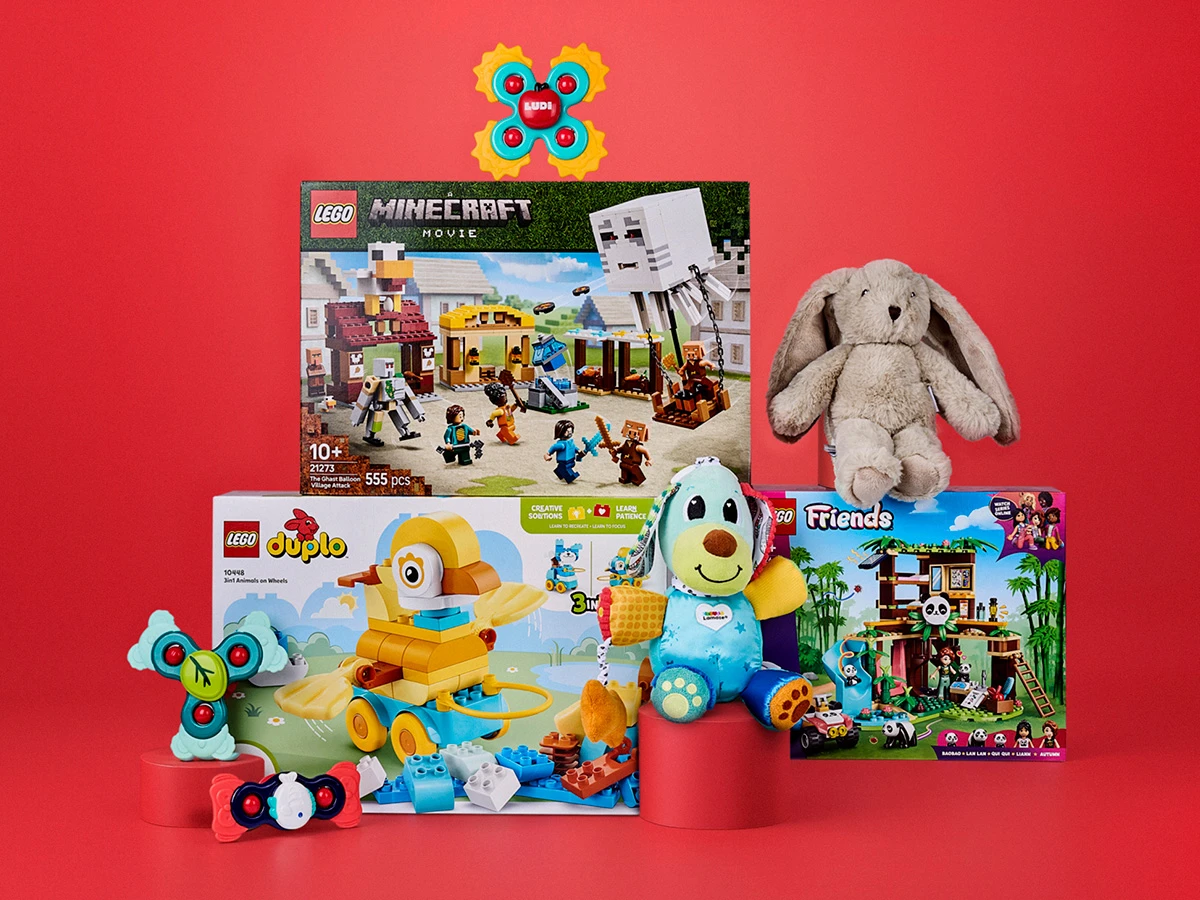 En samling legetøj: LEGO Minecraft, Duplo og Friends sæt, en kaninbamse, en hundebamse og farverigt sanselegetøj.