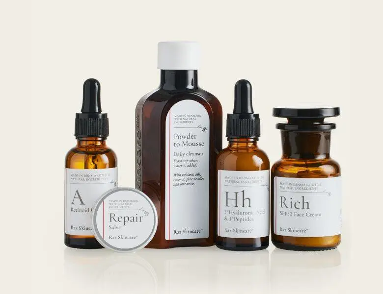 Her ses fem Raz Skincare produkter på en baggrund, som har en meget lysegul farve.