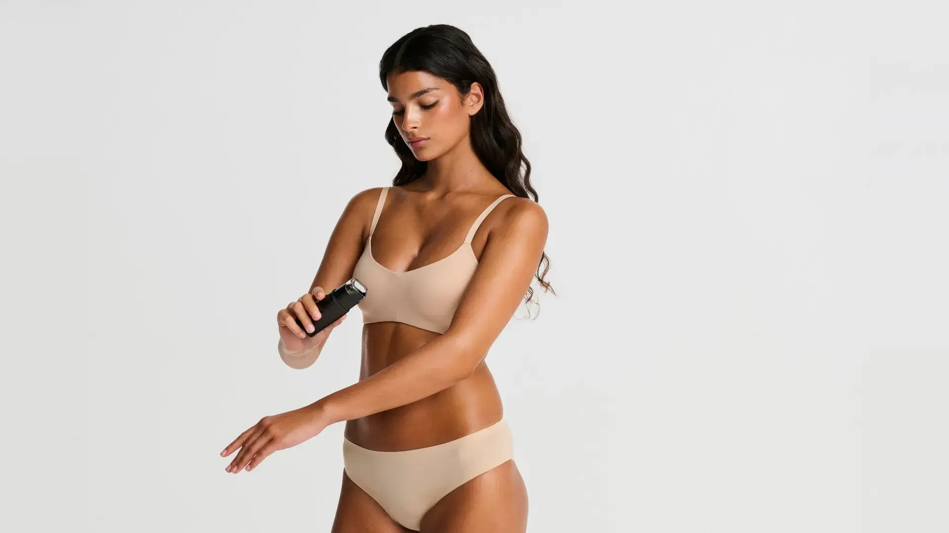 Kvinde påfører spraytan på armen med Tanrevel Spray Tan Device