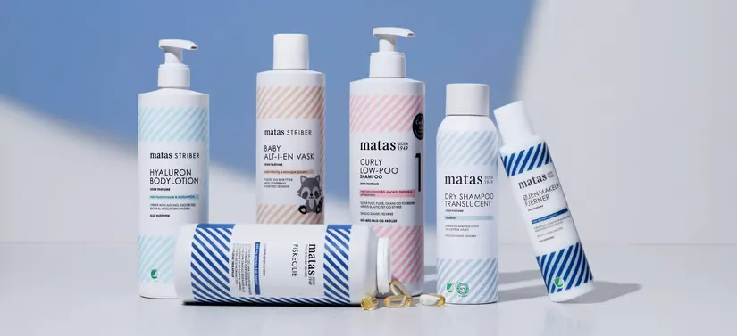 Her ses en blå og hvid baggrund med seks forskellige Matas Striber produkter i forskellige farvede striber. 