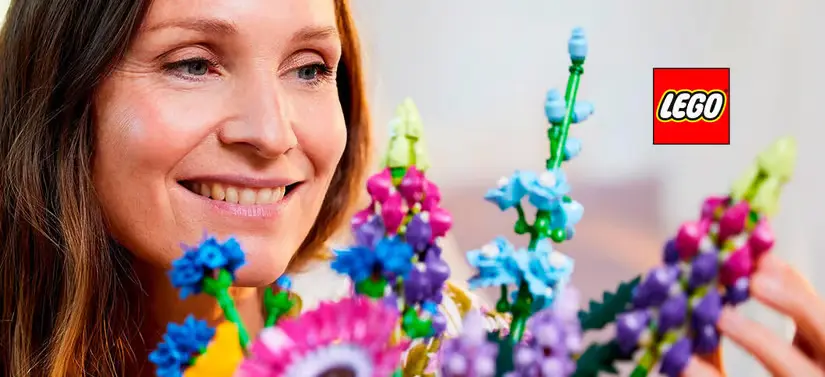 Her ses en glad kvinde, som holder en masse farverige Lego-blomster. Lego-logoet ses i øverste højre hjørne.