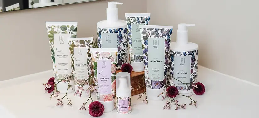 Her ses en masse forskellige produkter med blomster på. De står på en hvid overflade med blomster omkring sig.