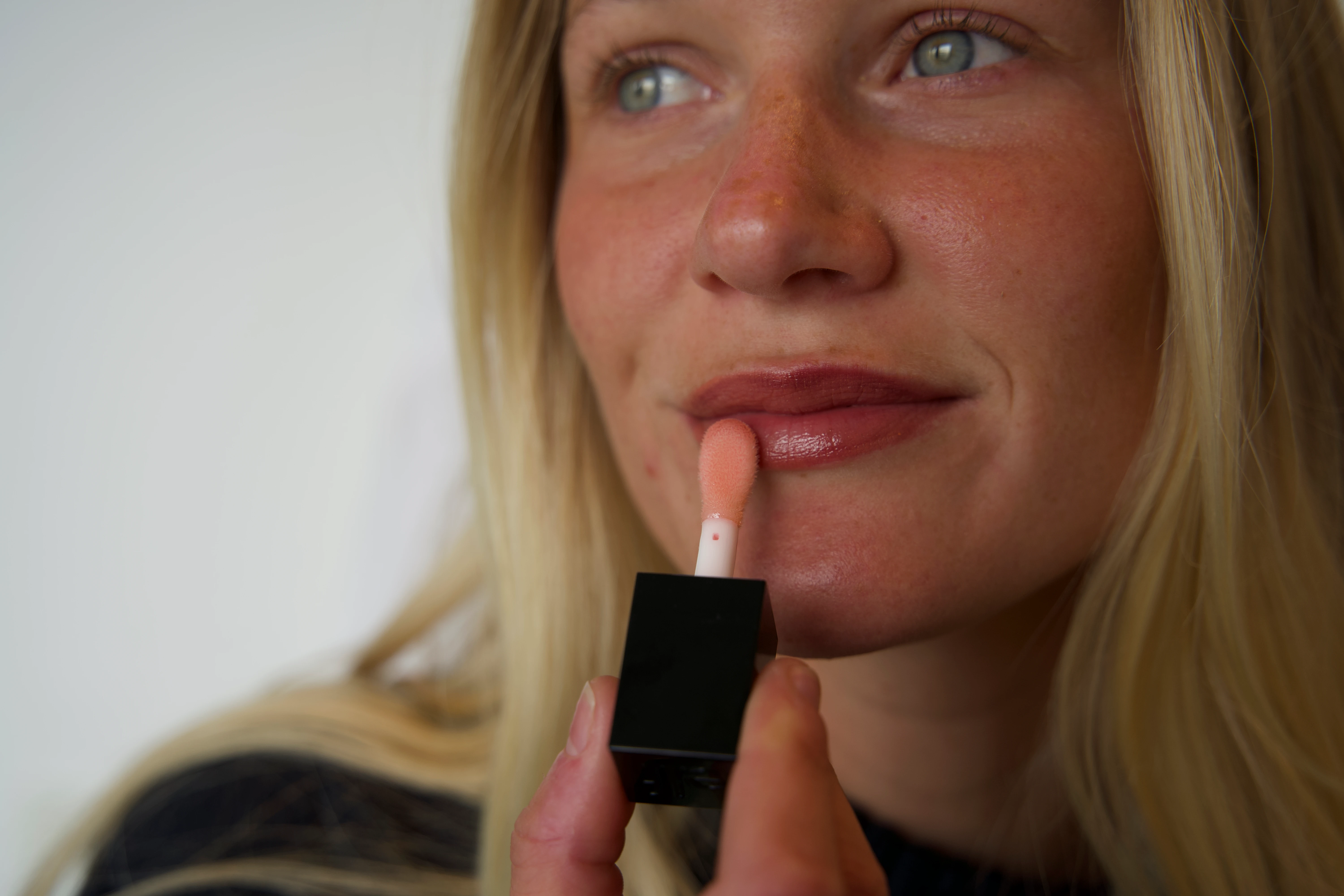 Kvinde, der tager lipgloss på læberne