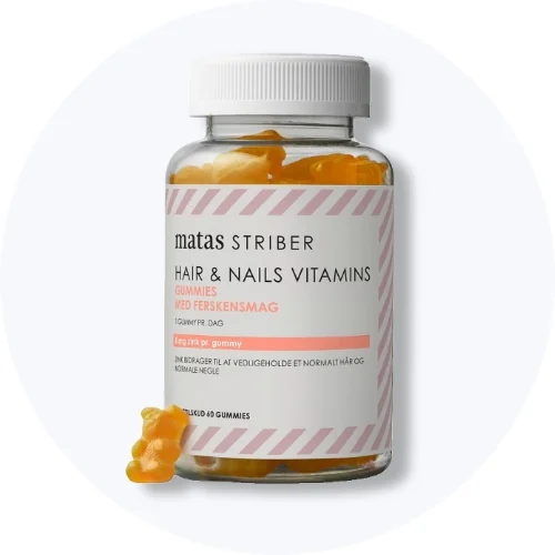 Matas Striber Hair & Nails Vitamins gummies i klar bøtte med ferskenfarvede vingummier og en gummy foran på lys grå baggrund.