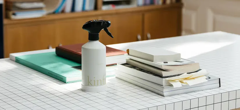 Her ses et Kinfill produkt i hvid. Det står på et hvidt bord af klinker, hvor der ligger flere bøger. 