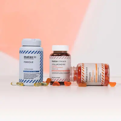 Her ses en lyserød/laksefarvet og hvid baggrund med tre Helse Matas Striber produkter. 