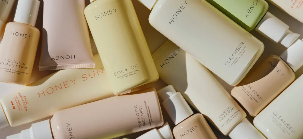 Her ses Honey hudplejeprodukter i lyse nuancer arrangeret på en lys baggrund.
