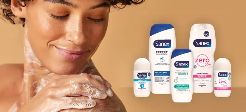 Her ses en, som smører sig ind i sæbe til venstre for fem Sanex produkter. Baggrunden er beige.
