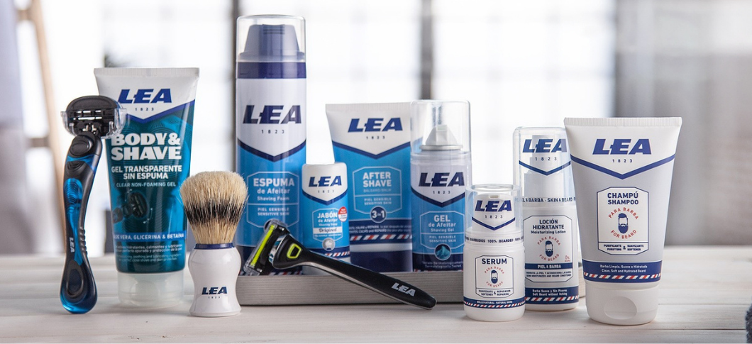 LEA barberings- og plejeprodukter står samlet på et bord, herunder skrabere, barberskum, aftershave, gel, sæbe, serum, lotion og skægshampoo.