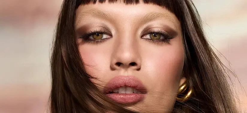 Her ses en kvindes ansigt. Hun har en makeup på, som ligger fokus på hendes øjne og læber. Baggrunden er slørret.