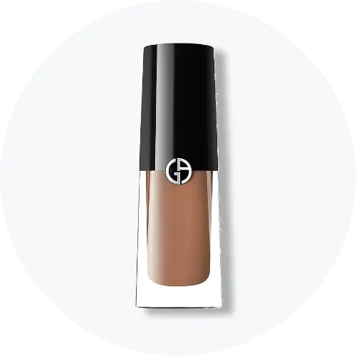 Her ses et billede af et makeup-produkt fra Giorgio Armani placeret centralt mod en lys, rund baggrund. Produktet er i klart glas med sort låg og har Giorgio Armani-logo på fronten.