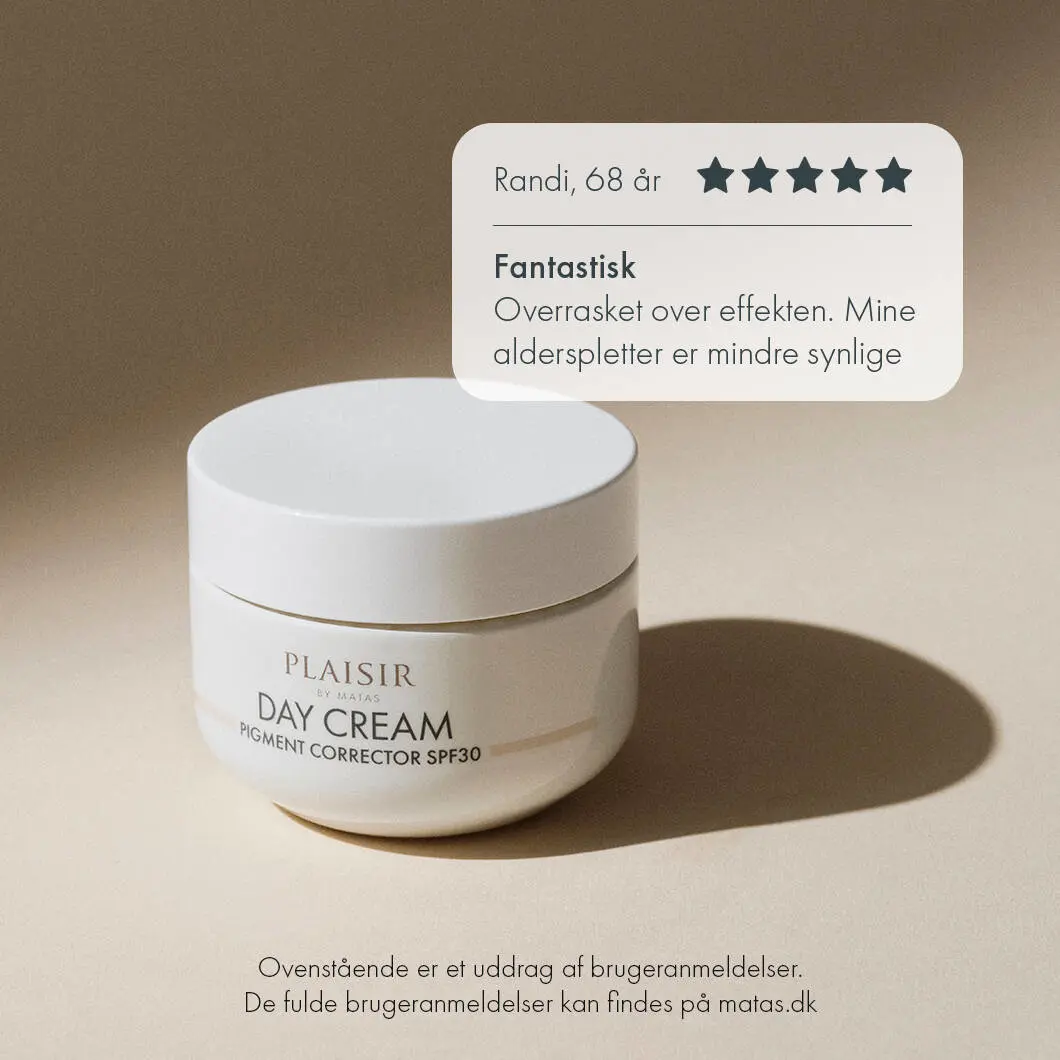 Et stilrent reklamebillede for “Plaisir Day Cream Pigment Corrector SPF30” fra Matas på en varm beige baggrund. Nederst til venstre står en rund, hvid dagcremekrukke med produktnavnet på forsiden. Krukken kaster en blød, oval skygge på underlaget, hvilket giver billedet dybde og et eksklusivt udtryk. Øverst til højre ses en hvid taleboble med en kundeanmeldelse fra “Randi, 68 år”. Anmeldelsen viser fem ud af fem stjerner og teksten: “Fantastisk – Overrasket over effekten. Mine alderspletter er mindre synlige”. Nederst i billedet står en note om, at anmeldelsen er et uddrag af brugeranmeldelser, og at de fulde anmeldelser kan findes på matas.dk. Billedet udstråler ro, kvalitet og effektiv hudpleje mod pigmentpletter.