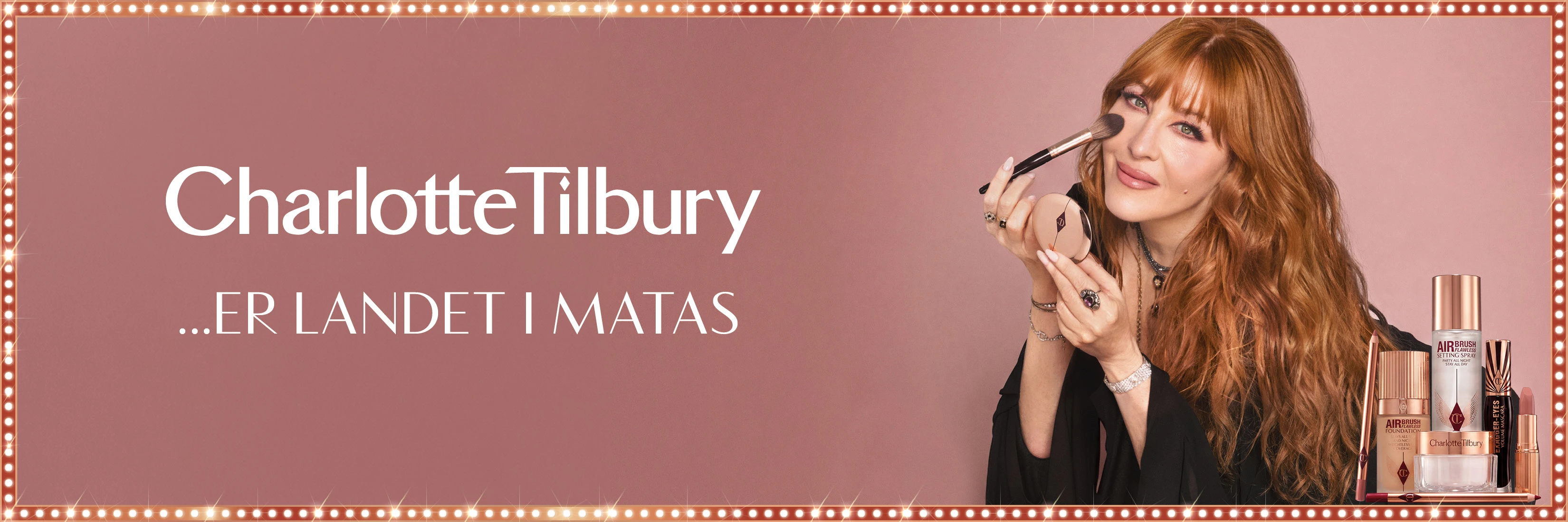 Charlotte Tilbury ...ER LANDET I MATAS. En kvinde påfører makeup, omgivet af Charlotte Tilbury skønhedsprodukter.