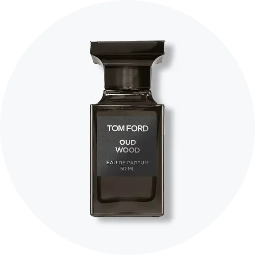 Her ses et billede af en parfumeflakon fra Tom Ford placeret centralt mod en lys, rund baggrund. På flakonen står teksten “TOM FORD OUD WOOD EAU DE PARFUM 50 ML”. Flakonen er i mørke nuancer med sort låg.