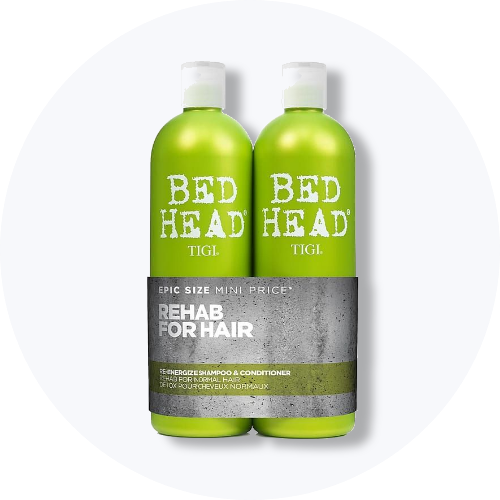 Her ses et billede med to hårplejeprodukter fra TIGI Bed Head placeret centralt mod en lys, rund baggrund. På flaskerne står teksten “BED HEAD TIGI” samt “REHAB FOR HAIR”. Produkterne er i grønne nuancer med hvide låg.