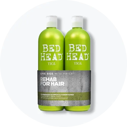 Her ses et billede med to hårplejeprodukter fra TIGI Bed Head placeret centralt mod en lys, rund baggrund. På flaskerne står teksten “BED HEAD TIGI” samt “REHAB FOR HAIR”. Produkterne er i grønne nuancer med hvide låg.