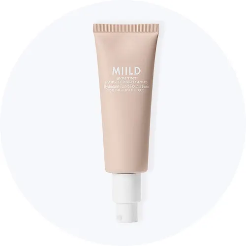 Her ses MIILD Skin Tint Moisturiser SPF 15 i en beige tube på en lysegrå cirkel.