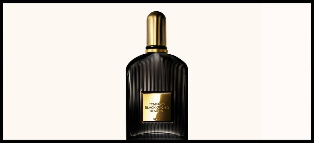 Her ses en sort parfumeflakon med guldlåg på en beige baggrund. Rundt om er en sort ramme.