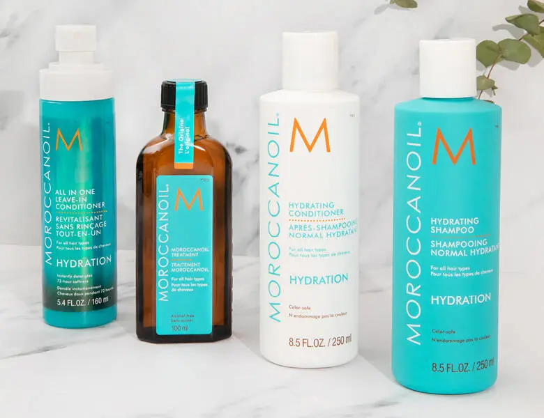 Her ses en lys baggrund med fire MoroccanOil produkter. 
