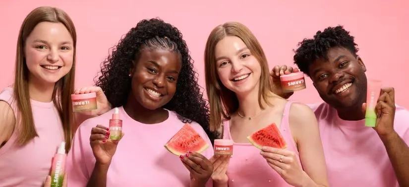 Her ses fire mennesker, som hver holder nogle Smuuti Skin produkter. Baggrunden er lyserød, ligesom deres trøjer. 