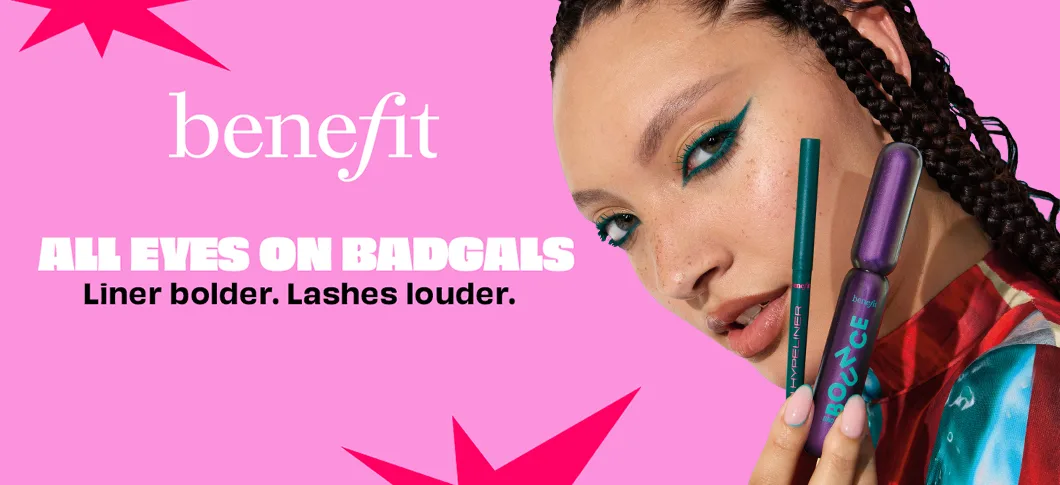Her ses et billede af en person mod en pink baggrund, der holder makeup-produkter fra Benefit op ved ansigtet. På billedet står teksten “benefit” samt “ALL EYES ON BADGALS – Liner bolder. Lashes louder.” Personen har markant grøn eyeliner, og produkterne omfatter eyeliner og mascara.