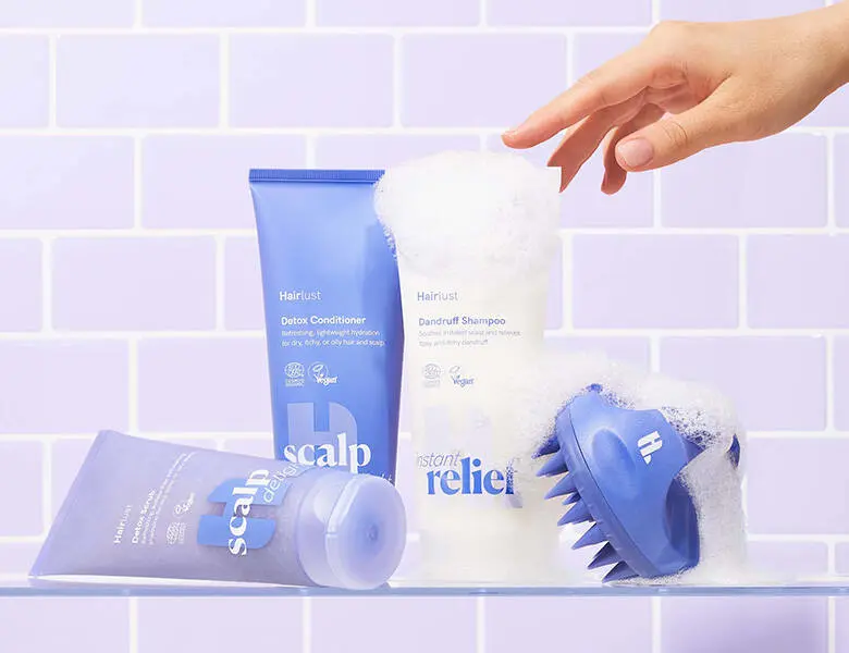 Her ses Hairlust produkter, hovedsageligt i lilla, på nogle lilla klinker og med sæbeskum.