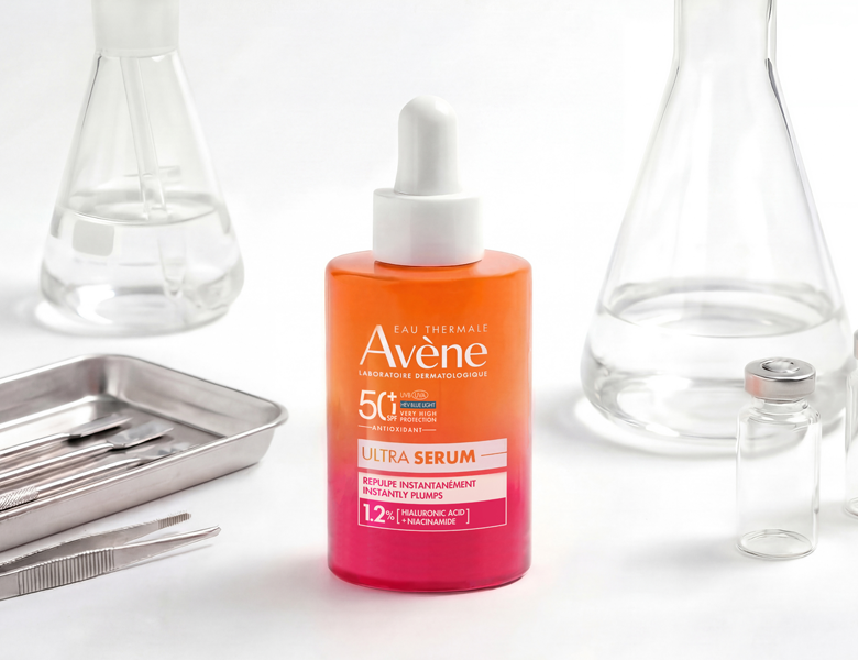 Her ses et Avène Ultra Serum i orange og pink emballage på en lys baggrund med glasbeholdere.