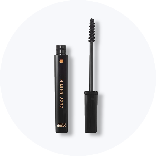 Her ses Nilens Jord Volume Mascara i sort emballage med guldfarvet tekst. Mascaraen er åben, så den sorte mascarabørste ses ved siden af beholderen, mod en lys baggrund.