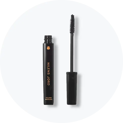 Her ses Nilens Jord Volume Mascara i sort emballage med guldfarvet tekst. Mascaraen er åben, så den sorte mascarabørste ses ved siden af beholderen, mod en lys baggrund.