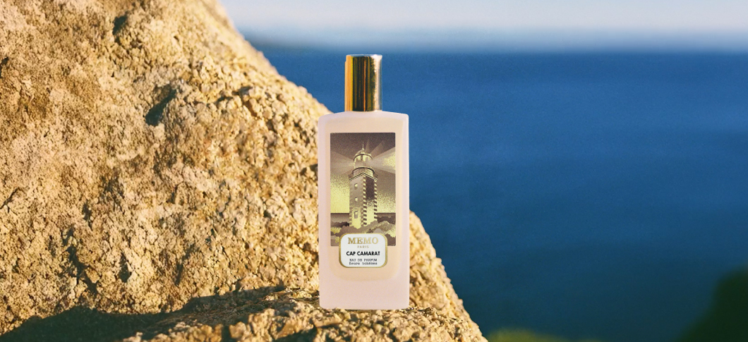 Her ses et billede af en parfumeflakon placeret på en klippe med havet i baggrunden. På flakonen står teksten “MEMO PARIS CAP CAMARAT”.