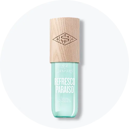 Her ses et billede af et body mist-produkt fra Sol de Janeiro placeret centralt mod en lys, rund baggrund. På produktet står teksten “SOL DE JANEIRO REFRESCO PARAISO”. Flasken er i turkis nuance med træfarvet låg.